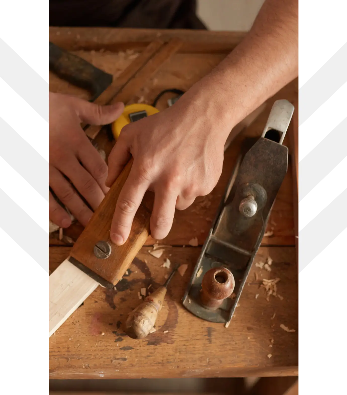 Hands using wood plane and tools.